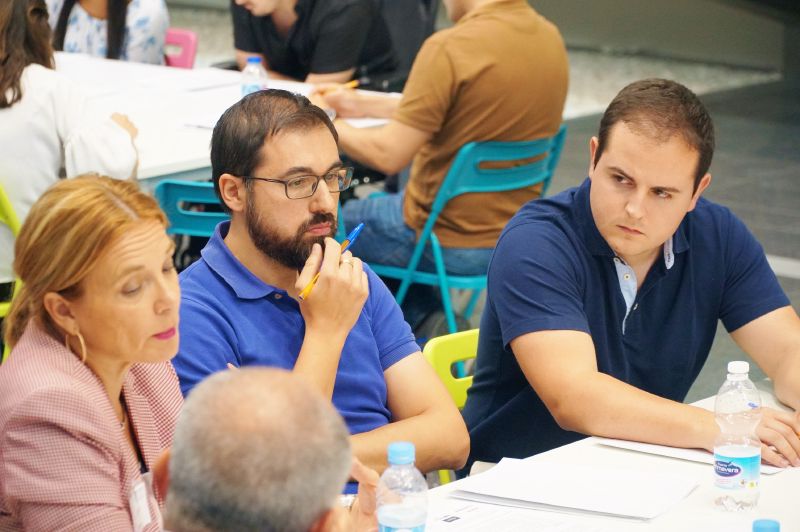 Una mujer y tres hombres sentados en una mesa hablando Equipos