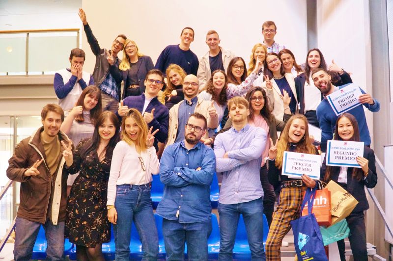 Varias personas en una grada de pie sonriendo con diplomas EmpleoWeekend